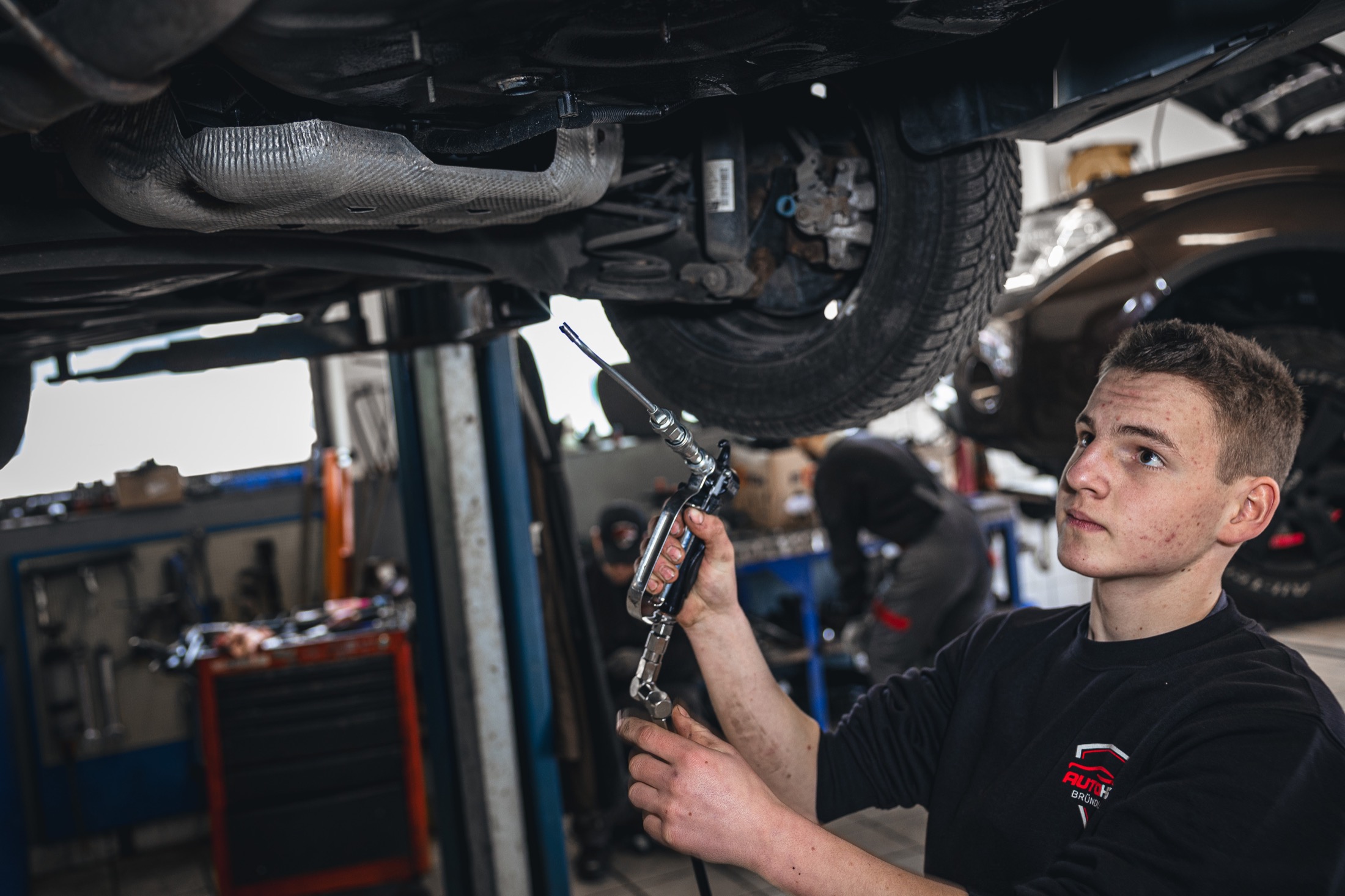 Mechaniker bei der Kontrolle unter dem Fahrzeug auf der Hebebühne